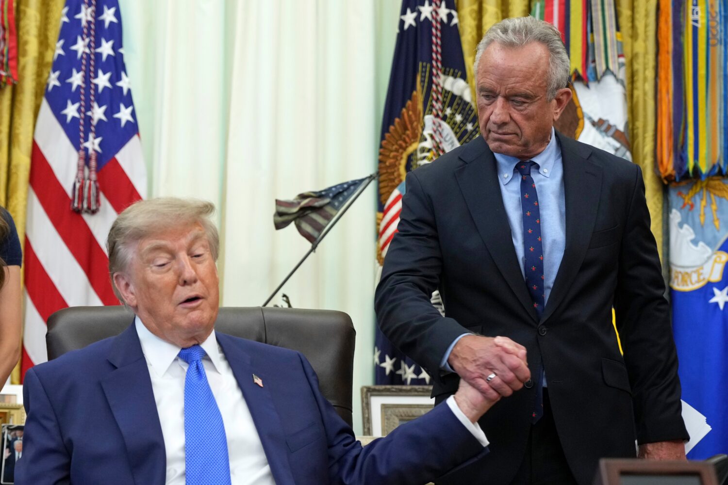 President Donald Trump, left, shakes the hand of Health and Human Services Secretary Robert F. Kenn...