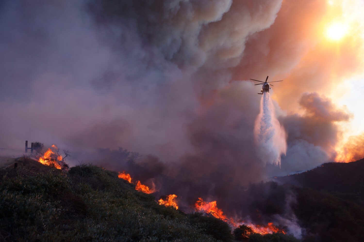 FILE - Water is dropped by helicopter on the advancing Palisades Fire in the Pacific Palisades neig...
