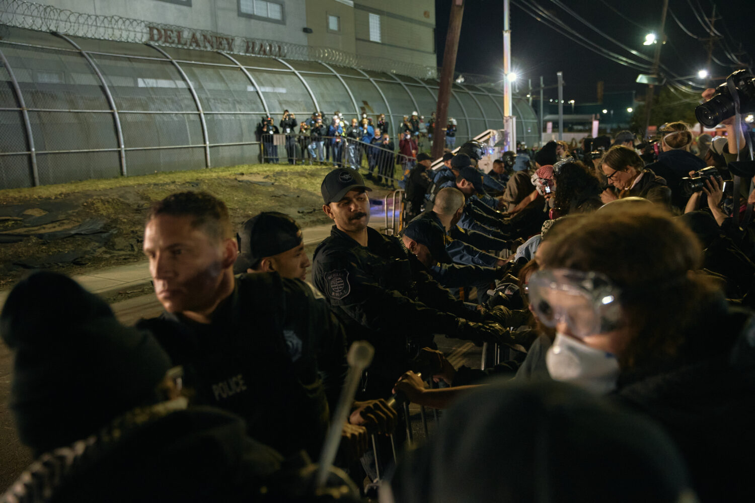 FILE - Police try to hold the line as protesters push the fences outside the Delaney Hall detention...