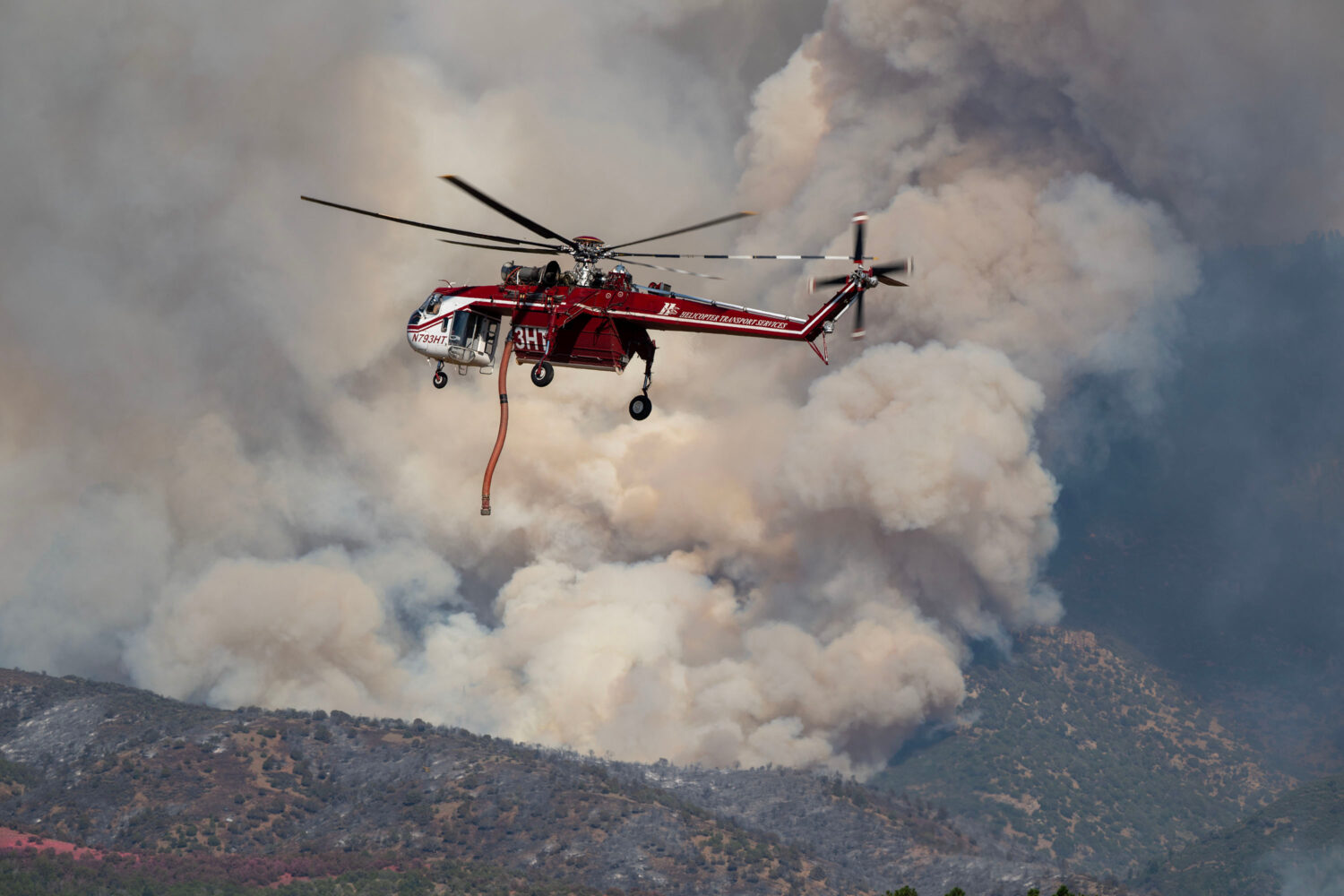 A Sikorsky Skycrane maneuvers into position to refill during efforts to fight the Widemouth 2 Fire ...