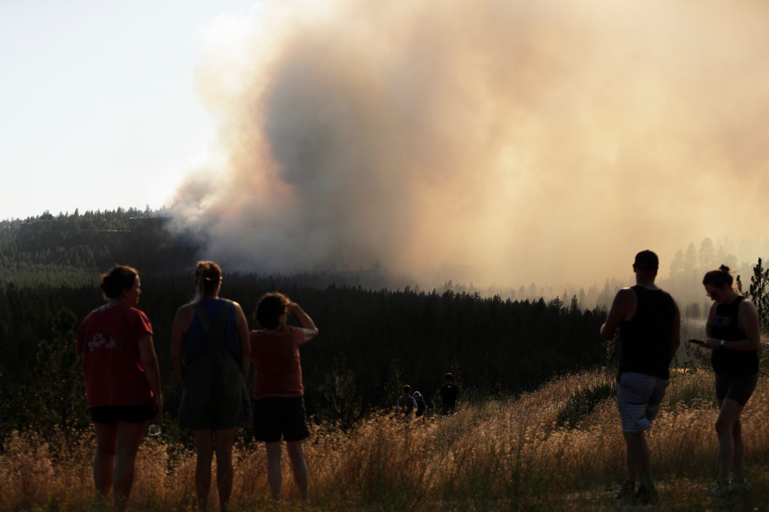 People watch Old Trails Fire from W. Northwest Blvd., Saturday, Aug. 1, 2026, in Spokane, Wash. (AP...