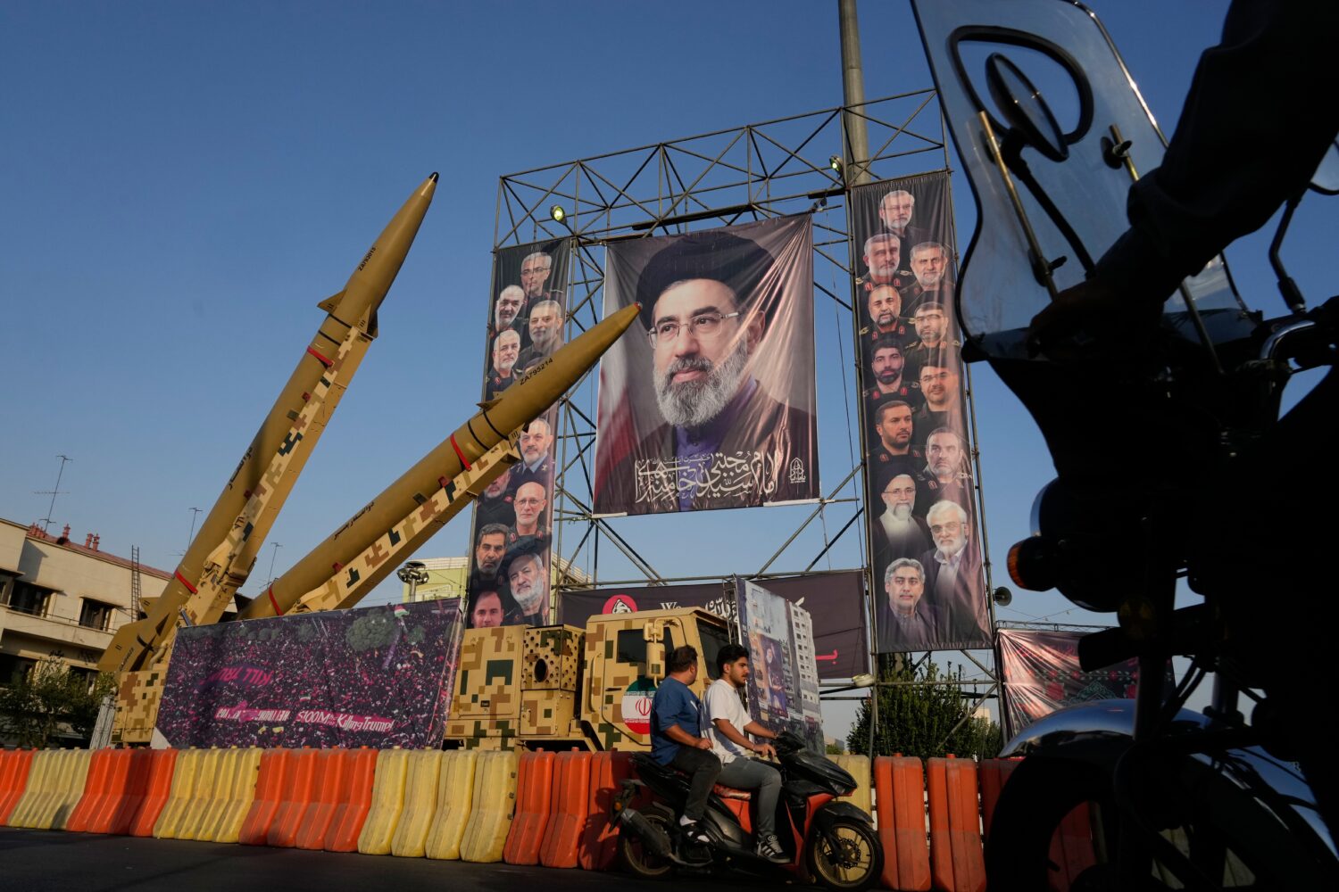 Motorbikes drive past Iranian missiles and banners showing portraits of the Iranian Supreme Leader ...