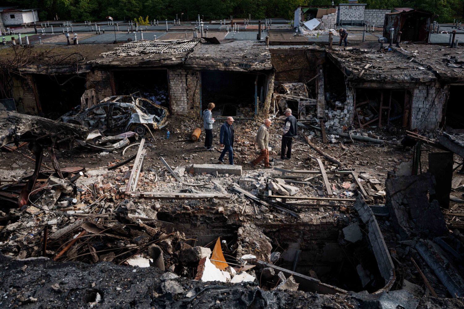 People walk in front of garages destroyed in a Russian missile strike on Vyshhorod, Kyiv region, Uk...