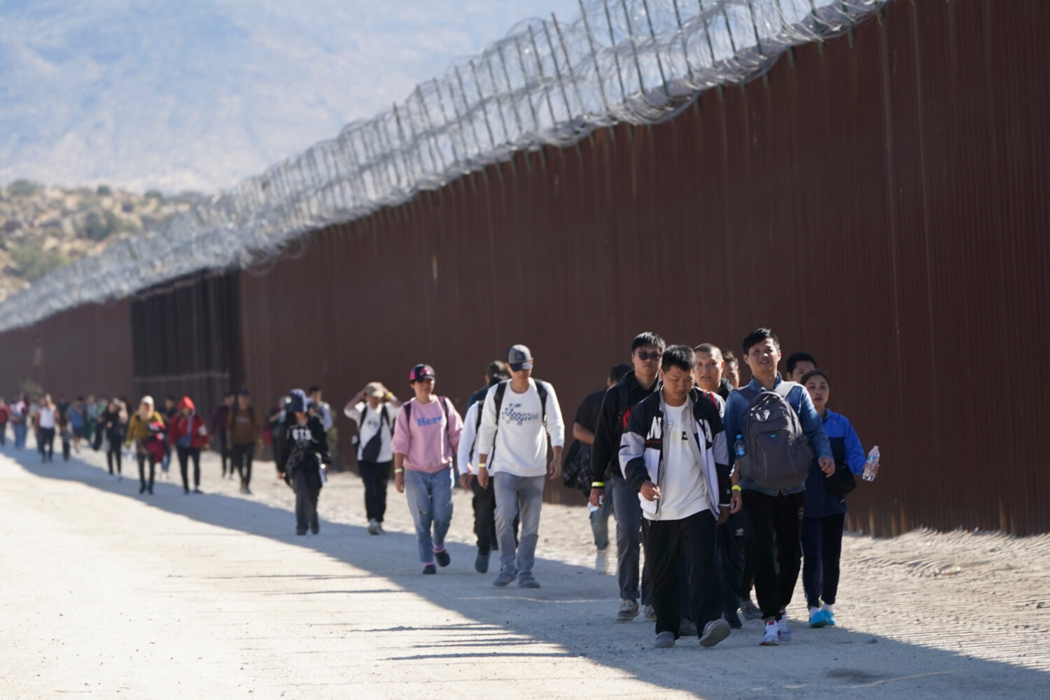 FILE - A group of people, including many from China, walk along the wall after crossing the border ...