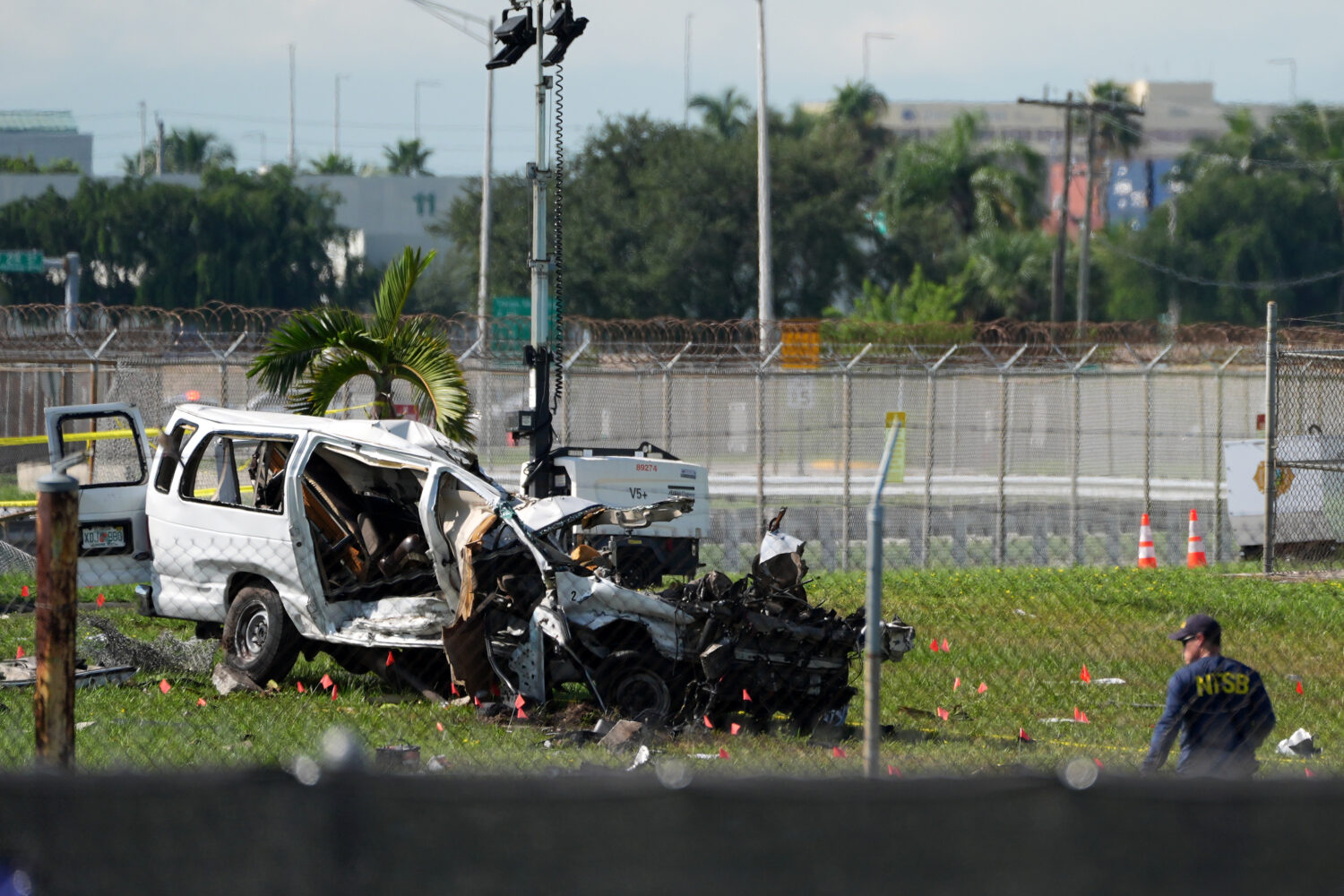 An NTSB investigator works near a damaged van at the site where an Amazon cargo plane overshot the ...