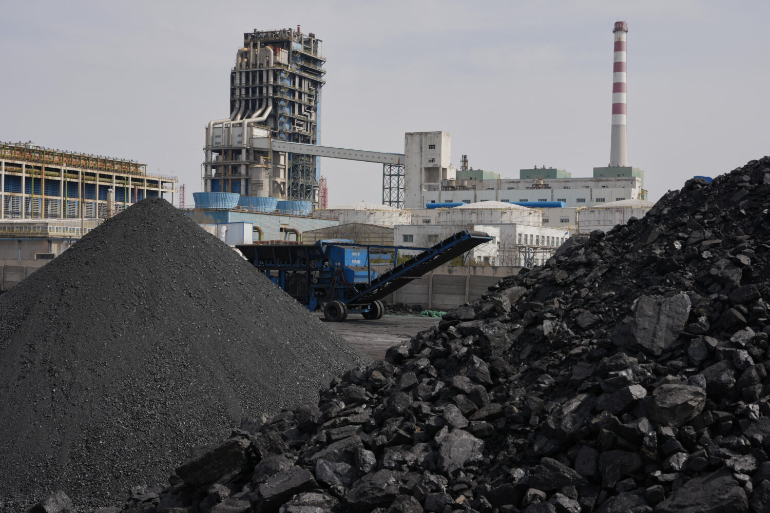 FILE - Piles of coal sit near a chemical plant in Datong, China, March 14, 2026. (AP Photo/Ng Han G...