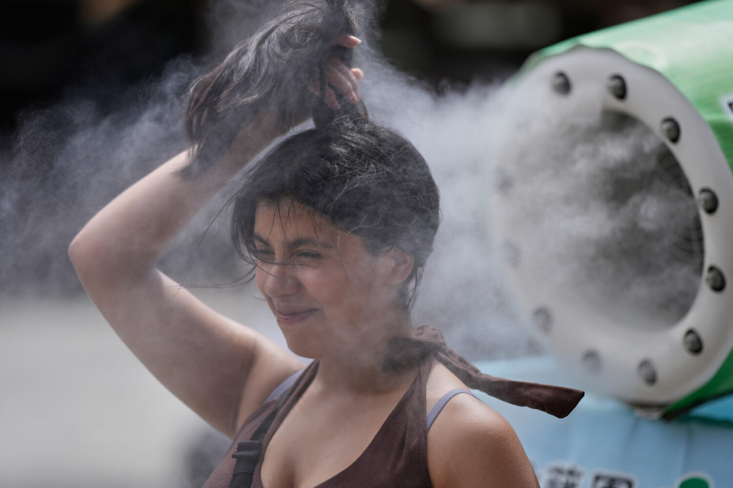 FILE - A person cools off at a cooling mist spot on a hot and sunny day at the Sensoji Buddhist tem...