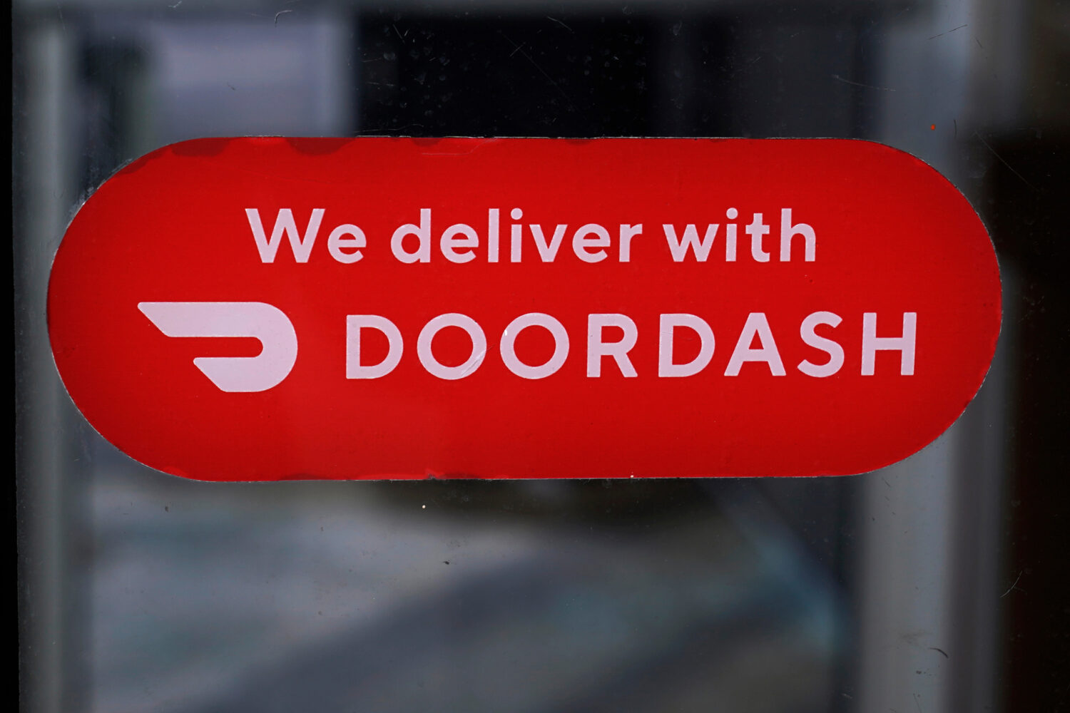 FILE - A DoorDash sign is posted on a door, Feb. 27, 2023, in Methuen, Mass. (AP Photo/Charles Krup...