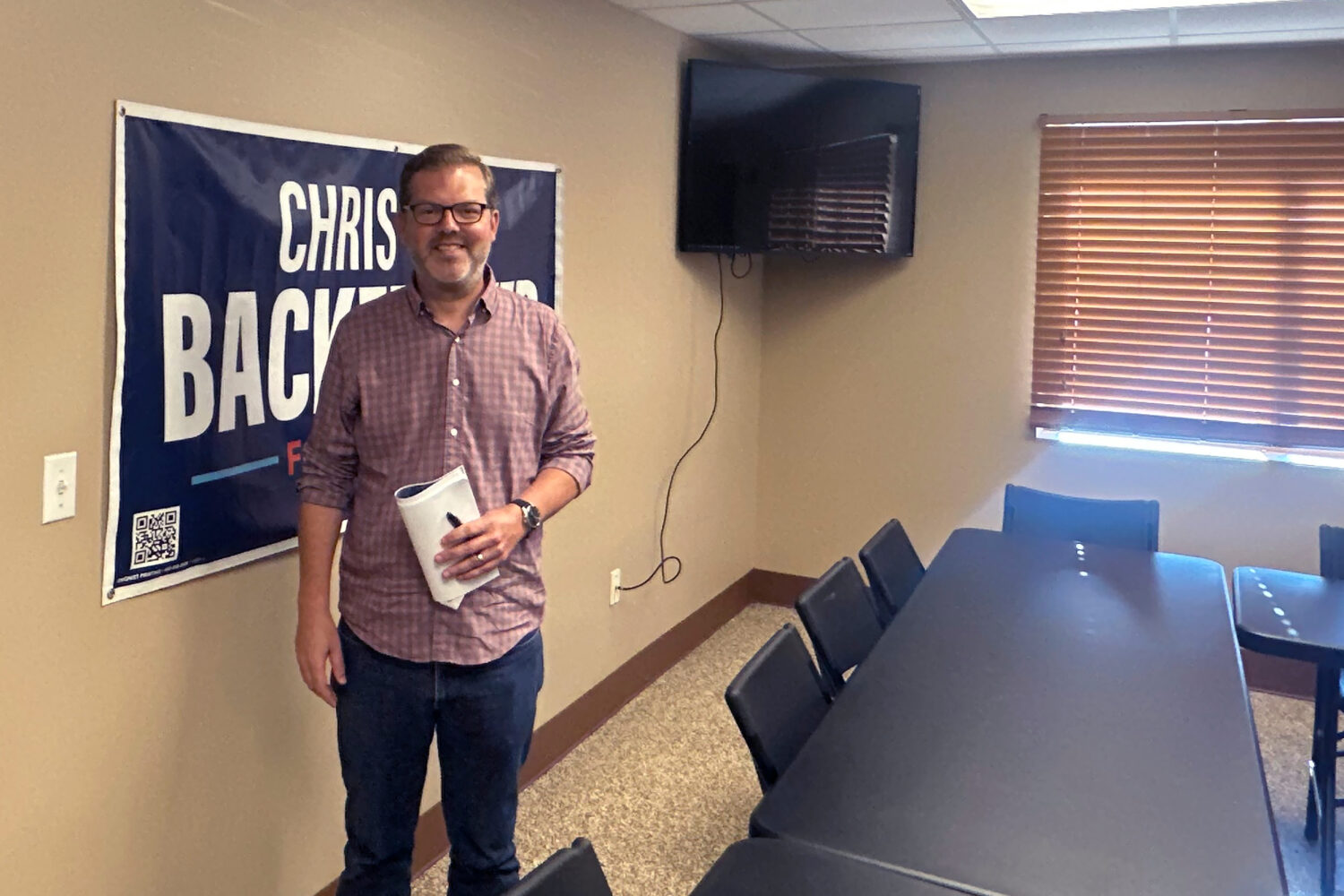 Democratic congressional candidate Chris Backemeyer poses in front of a campaign banner after an ev...