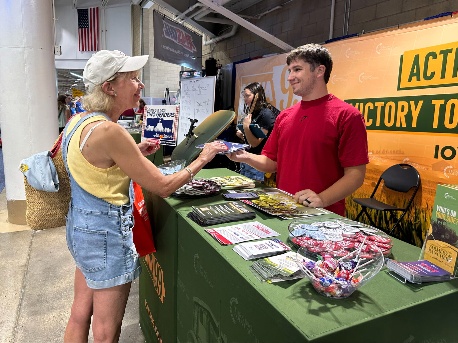 A Turning Point Action staffer gives an American flag to a voter at the Iowa State Fair in Des Moin...