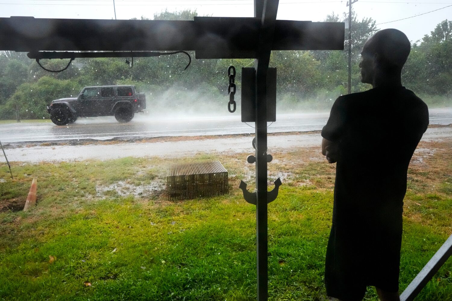 Michael Espinoza stands under the awning of his shop, T&M Bait Shop, watching rain from Tropical St...