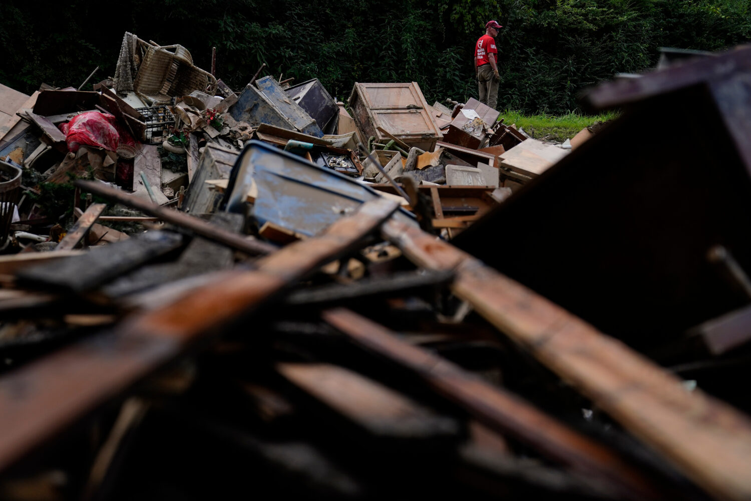 FILE - A man stands near a pile of debris as residents clean up in Fleming-Neon, Ky., Aug. 5, 2022,...
