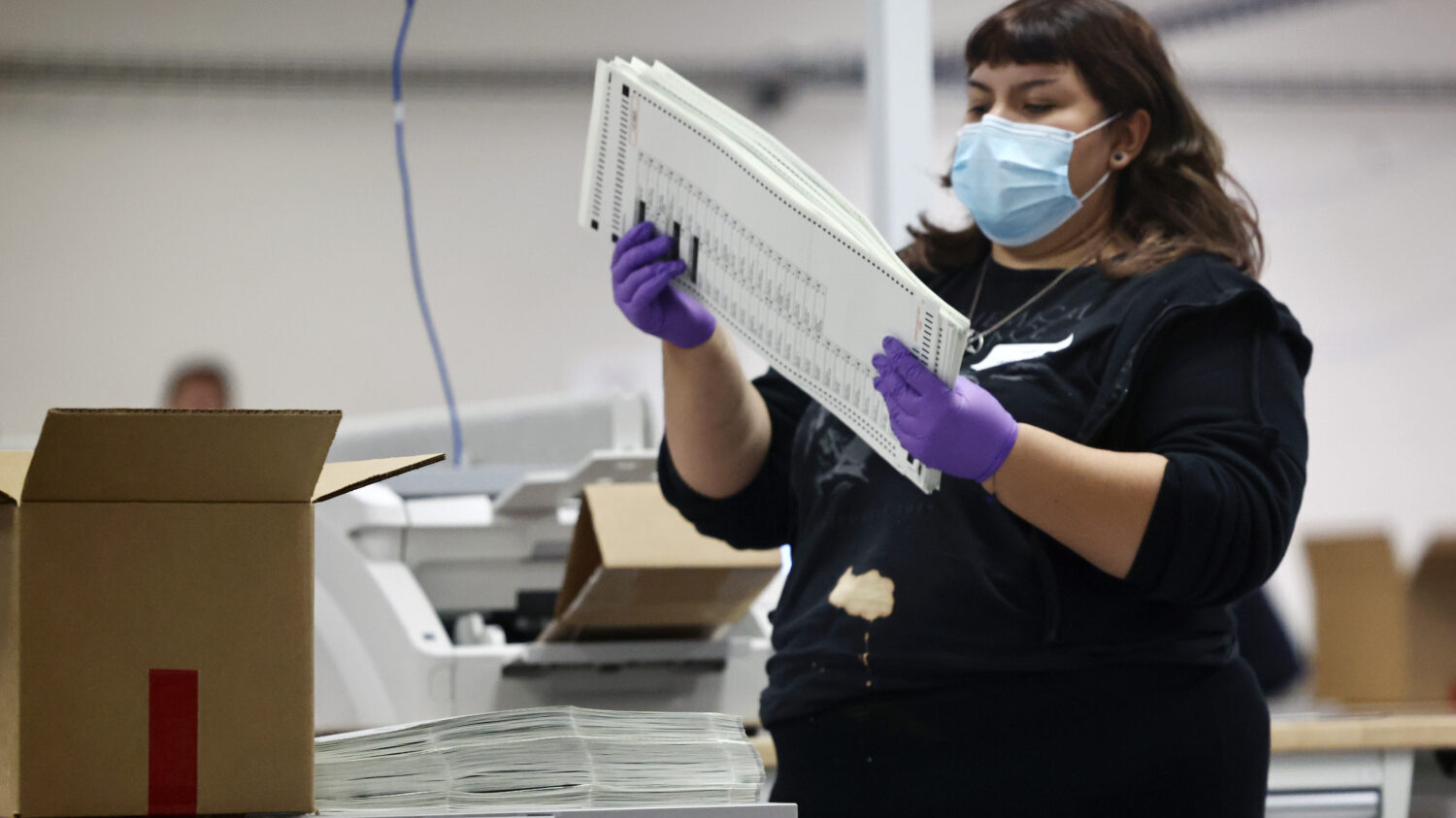 An election worker processes early ballots inside the Maricopa County Tabulation and Election Cente...