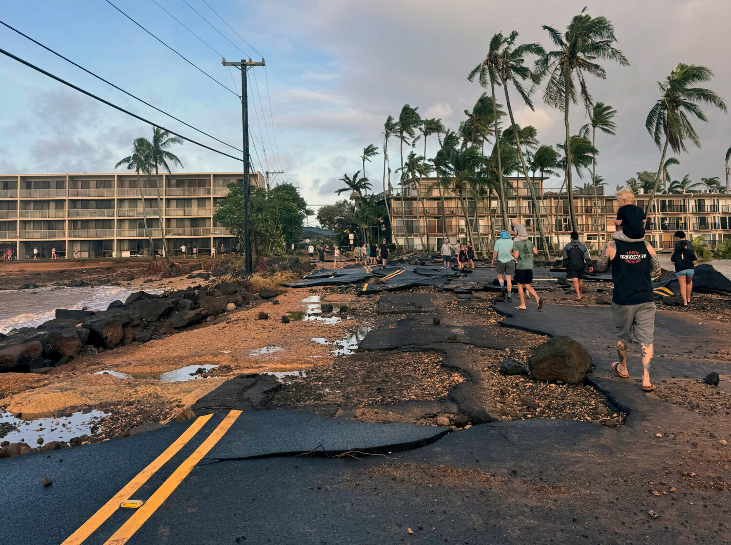 This photo taken with a smartphone, People walk past damage caused by Hurricane Lowell on Tuesday, ...