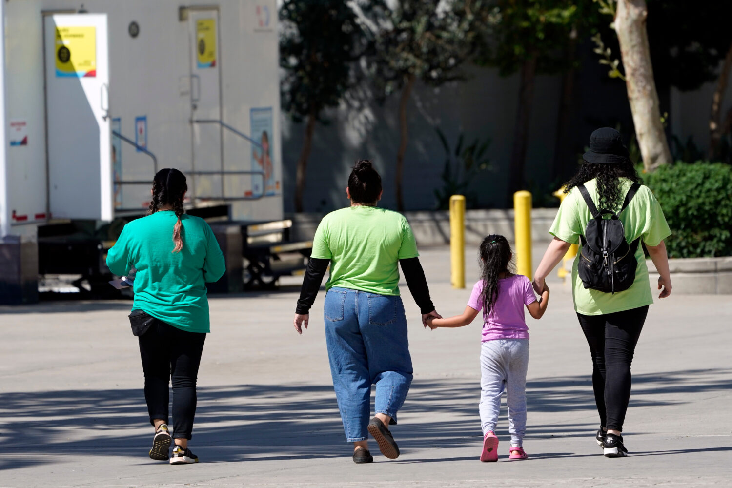 FILE - A child holds hands with workers at an emergency shelter for migrant children, July 2, 2021,...