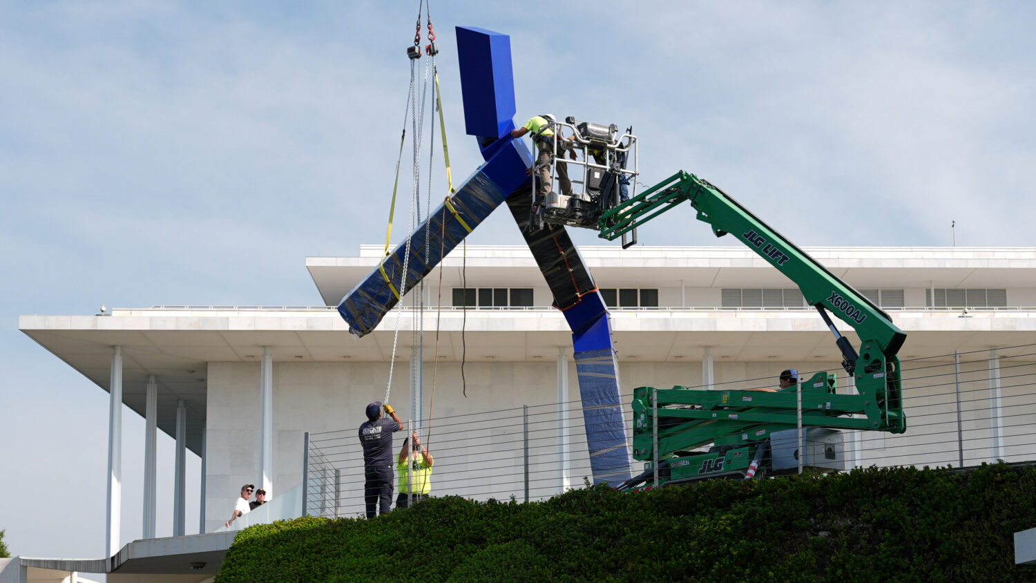 Workers remove the sculpture "Blue" by artist Joel Shapiro on the grounds of the John F. Kennedy Ce...