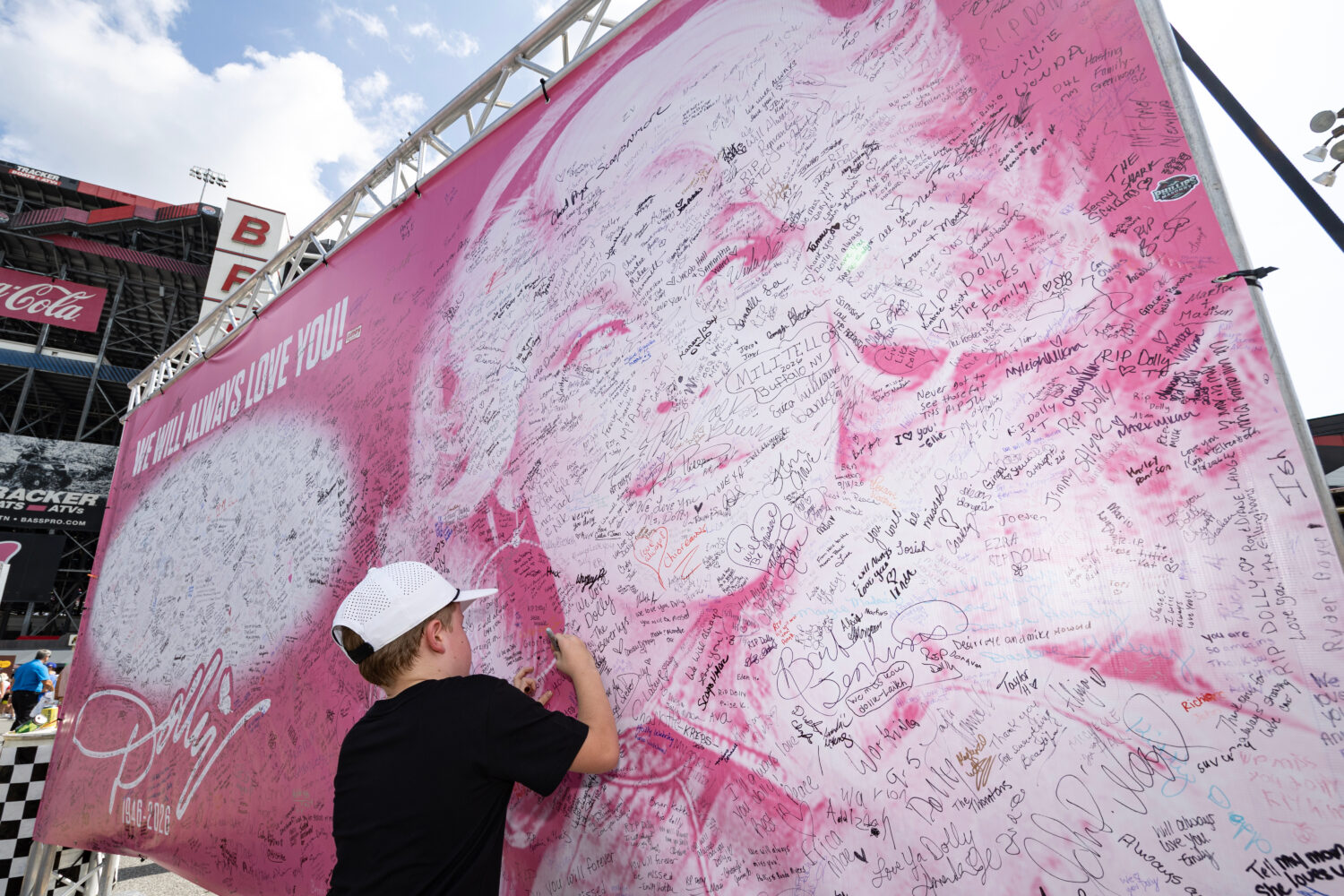Henry Bailey, 7, from Kentucky signs his name to a tribute sign to the late Dolly Parton before a N...