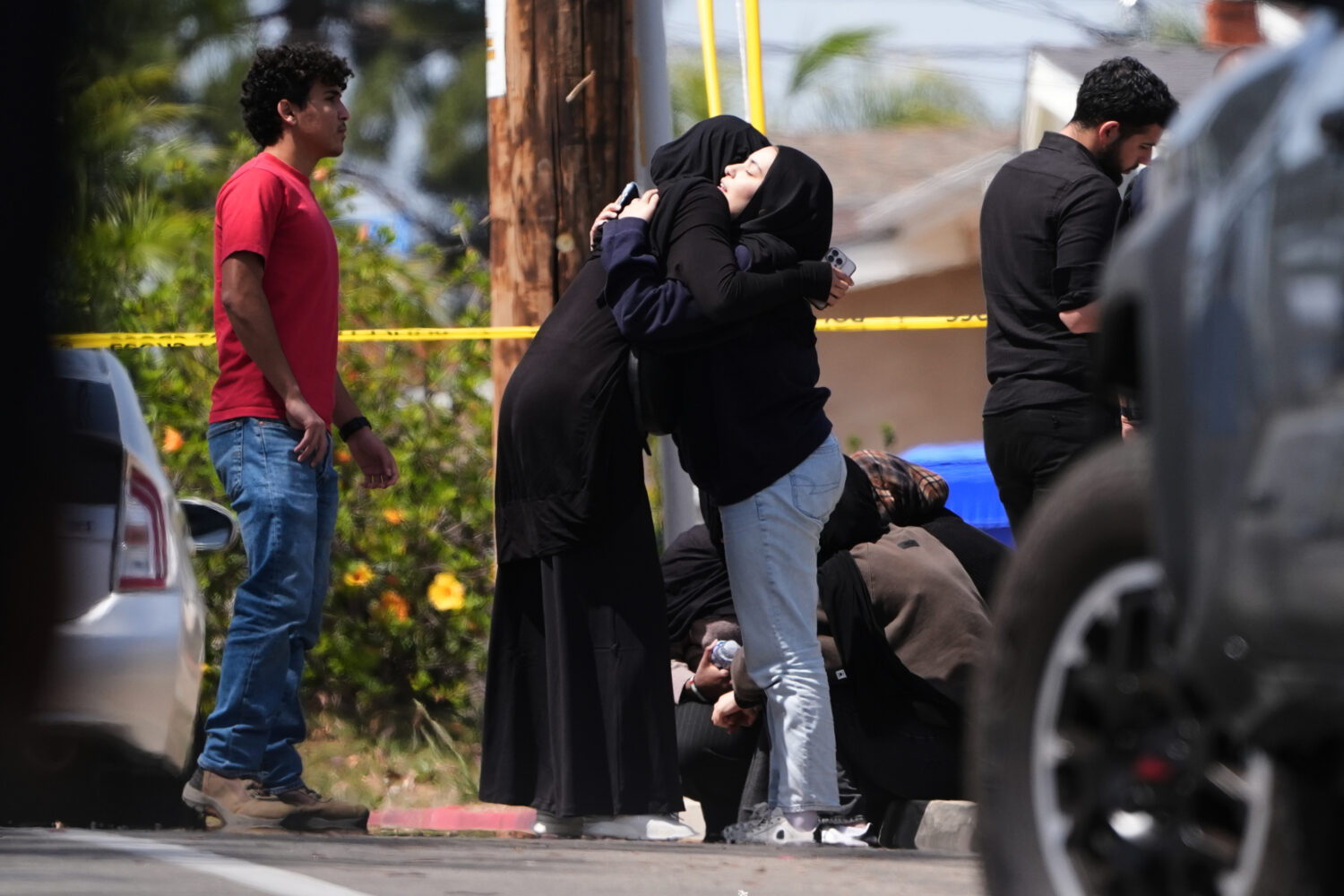 FILE - People embrace near the scene of a shooting outside the Islamic Center in San Diego, May 18,...