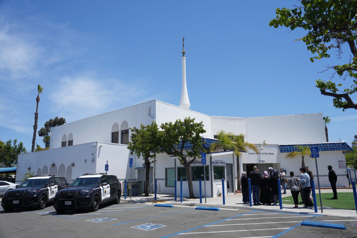 FILE - People gather as police vehicles are parked outside of the Islamic Center of San Diego, the ...