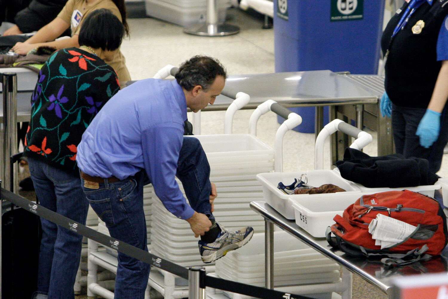 FILE - An airline passenger pulls off his shoes to be scanned as he prepares to go through a securi...