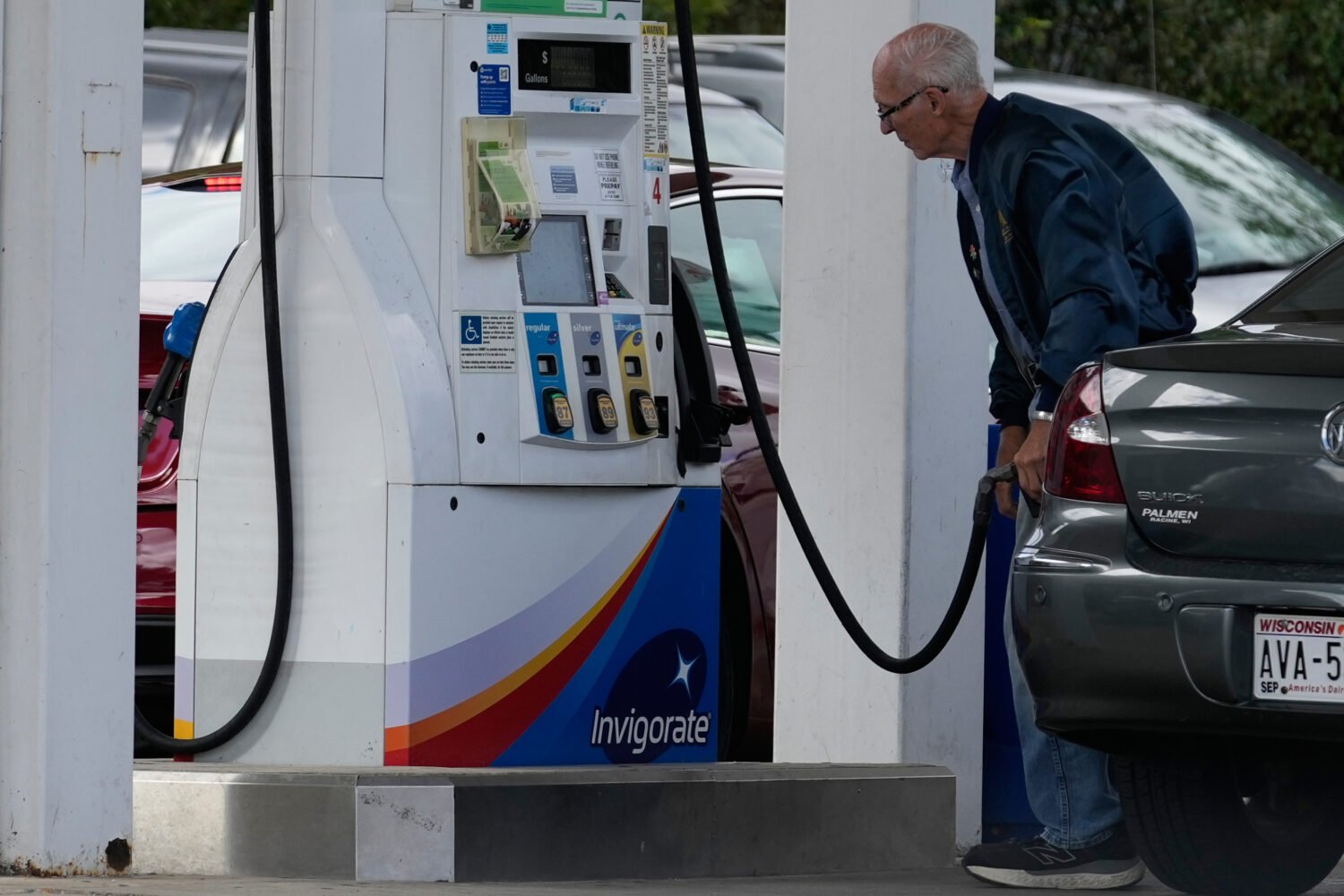 A customer checks gas price while he fills up his vehicle's tank at a gas station in Racine, Wis., ...