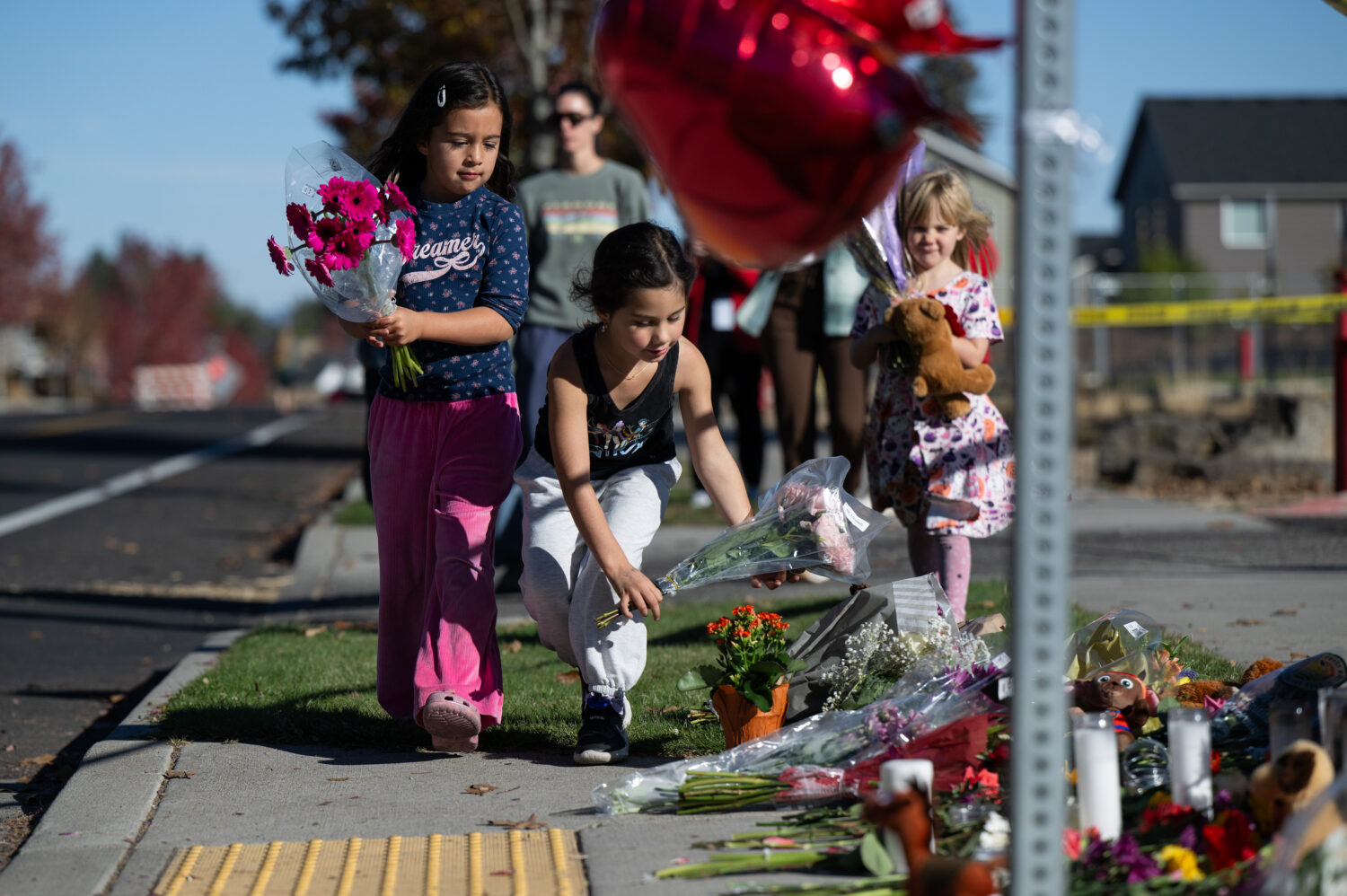 Children place flowers at a makeshift memorial outside Silver Rail Elementary in Bend, Ore., Friday...