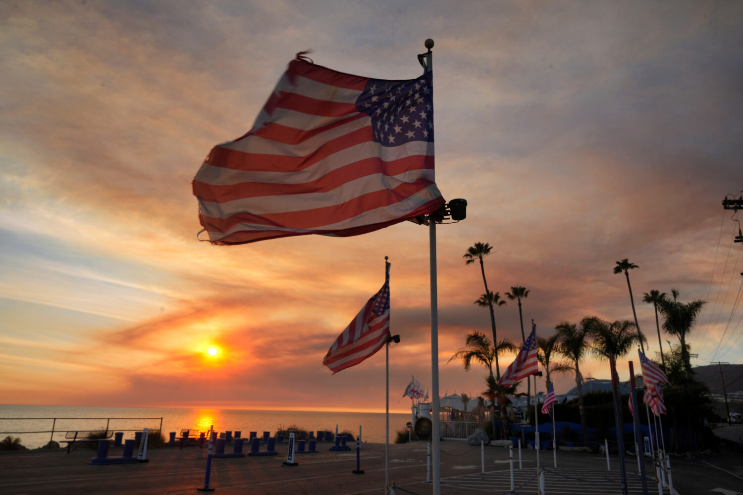 FILE - Flags fly under heavy winds before sunset as a plume of smoke from the Franklin Fire rises o...