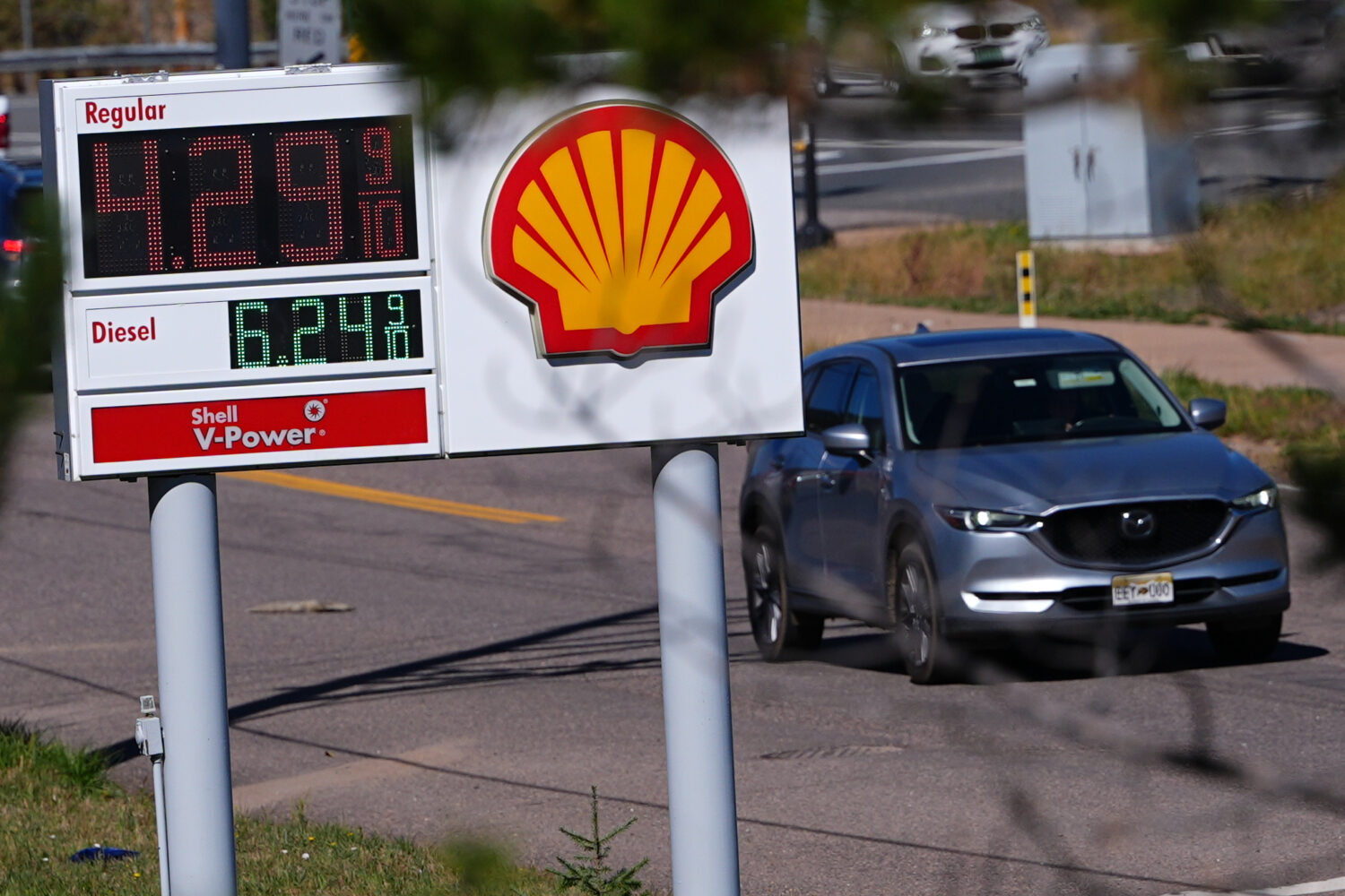 A motorist drives past a sign posting the per-gallon prices for regular unleaded and diesel fuel at...