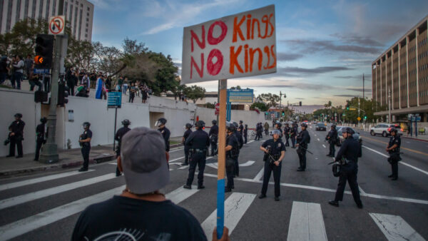 A man holds a sign near the Metropolitan Detention Center to protest immigration enforcement and Federal overreach during a national 'No Kings' protest on March 28, 2026 in Los Angeles, California. This is the third nationwide "No Kings" protest held against the Trump administration. (Photo by Apu Gomes/Getty Images)
