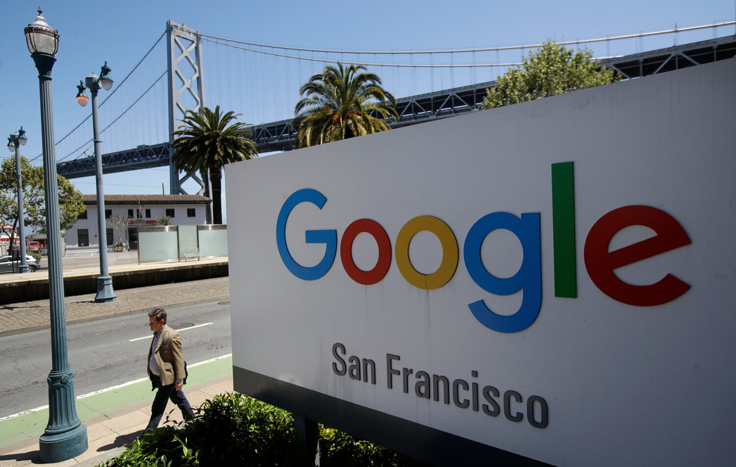 FILE - In this May 1, 2019, file photo a man walks past a Google sign outside with a span of the Ba...