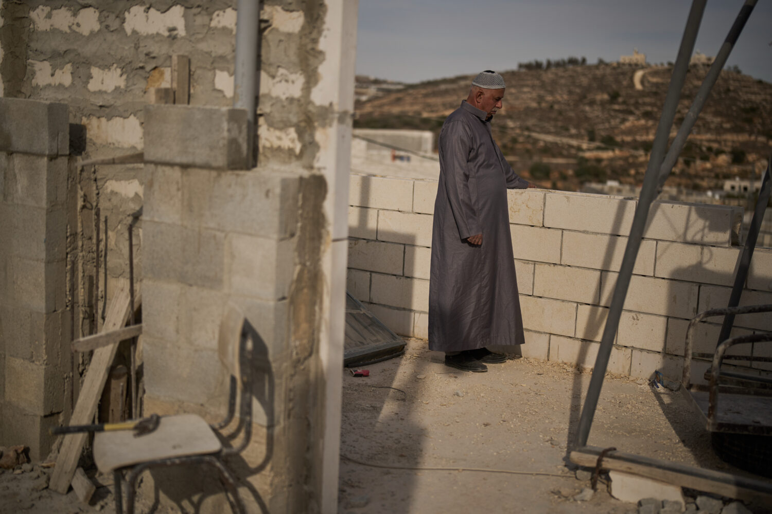 Mahmoud Tubasi stands on a rooftop near his two family's houses, which were burned by Israeli settl...