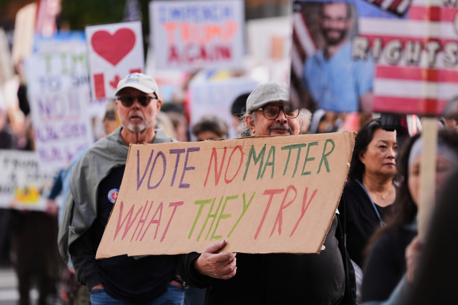 A person holds a sign during a "No Kings" protest march encouraging early voting Saturday, Oct. 17,...