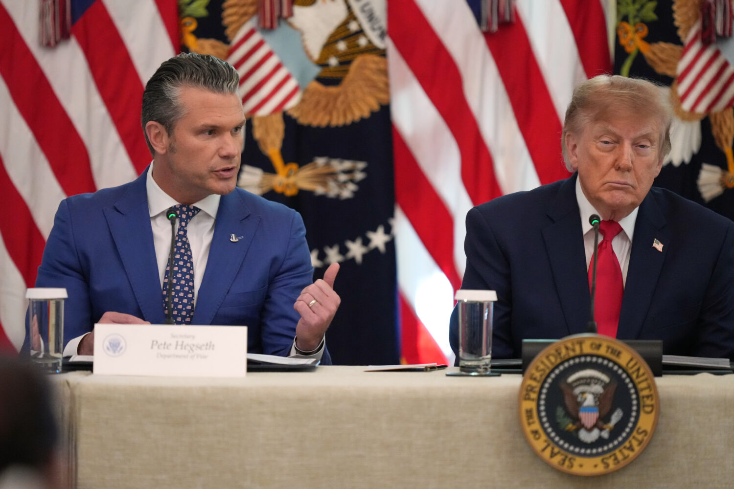 President Donald Trump listens as Defense Secretary Pete Hegseth speaks at a roundtable event in th...