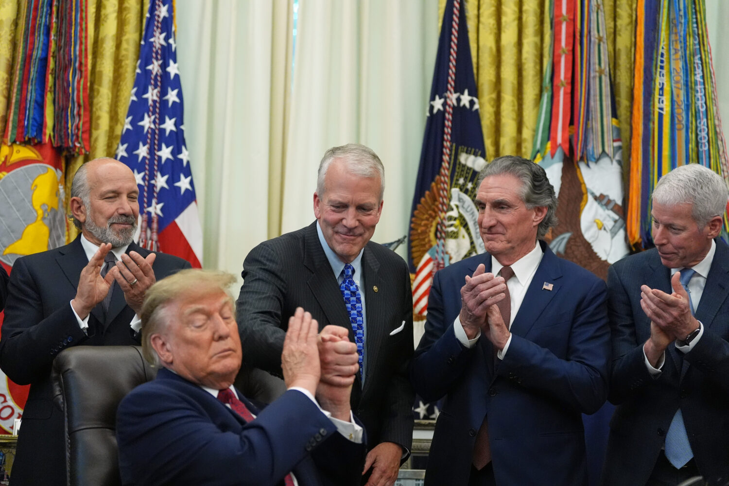 President Donald Trump shakes hands with Sen. Dan Sullivan, R-Alaska, as he speaks in the Oval Offi...