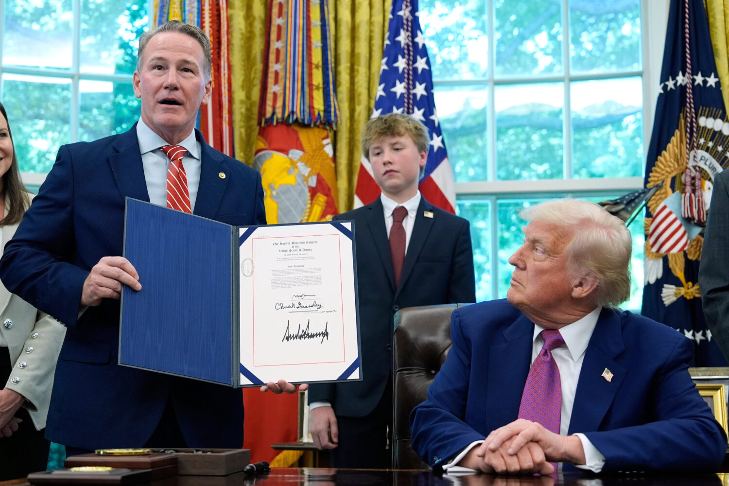 FILE - President Donald Trump listens as Sen. Jon Husted, R-Ohio, speaks while holding up a signed ...