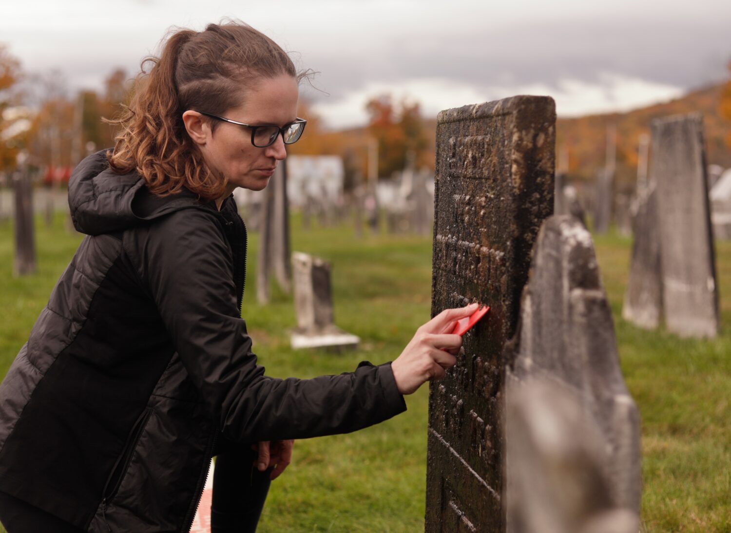 Caitlin Abrams, who became popular on TikTok for her grave cleaning videos, scrapes away moss and l...