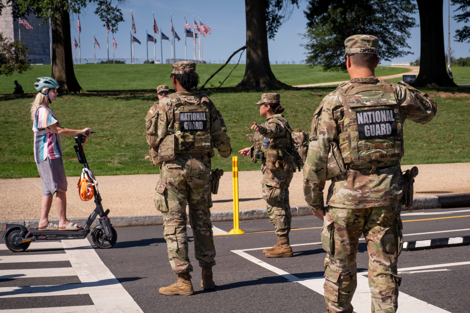National Guard troops stop a young woman on a rental scooter near a closed intersection where Presi...