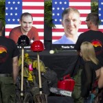 Alumni of the Granite Mountain Hotshots converse in front of the stage that displays photographs of the 19 fallen firefighters before the "Our Fallen Brother" memorial service at Tim's Toyota Center in Prescott Valley, Ariz. on Tuesday, July 9, 2013. Prescott's Granite Mountain Hotshots were overrun by smoke and fire while battling a blaze on a ridge in Yarnell, about 80 miles northwest of Phoenix on June 30, 2013. (AP Photo/The Arizona Republic, David Wallace, Pool)

