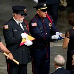 A flag is presented to Juliann Ashcraft, widow of fallen firefighter Andrew Ashcraft, during a memorial service for the 19 fallen firefighters at Tim's Toyota Center in Prescott Valley, Ariz. on Tuesday, July 9, 2013. Prescott's Granite Mountain Hotshots were overrun by smoke and fire while battling a blaze on a ridge in Yarnell, about 80 miles northwest of Phoenix on June 30, 2013. (AP Photo/The Arizona Republic, Michael Chow, Pool)