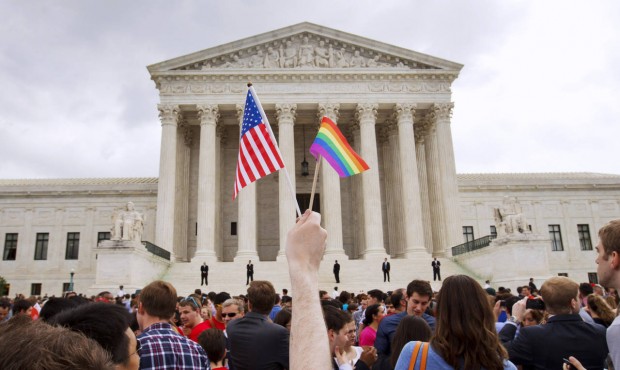 n FILE – In this Friday June 26, 2015, file photo, a man holds a U.S. and a rainbow flag outs...