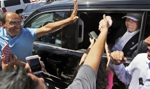 Supporters reach to great Republican presidential hopeful Donald Trump as he leaves a brief stop to...