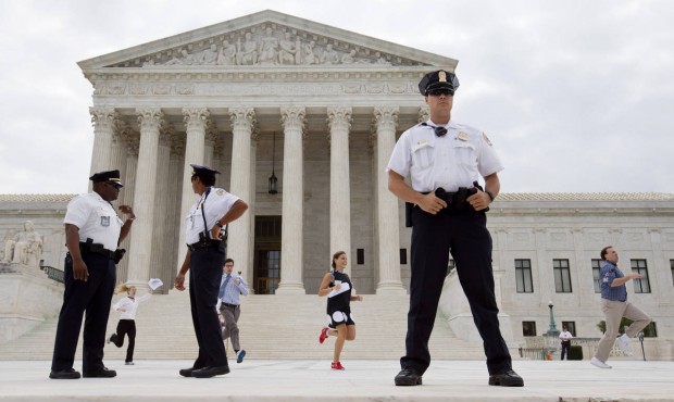 Interns run behind a line of security outside of the Supreme Court in Washington, Friday June 26, 2...