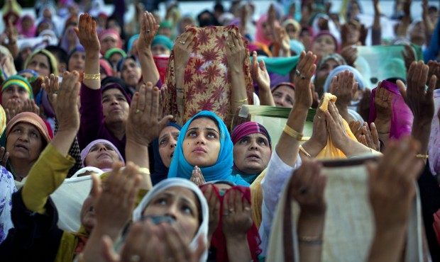 Kashmiri Muslim devotees raise their hands in prayer as a head priest displays a relic of the Proph...