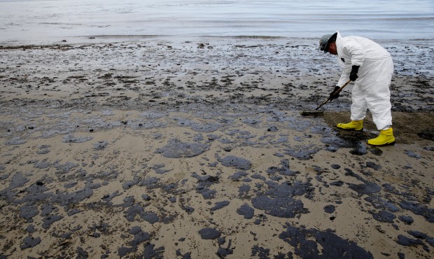 A worker removes oil from the beach at Refugio State Beach, north of Goleta, Calif., Thursday, May ...