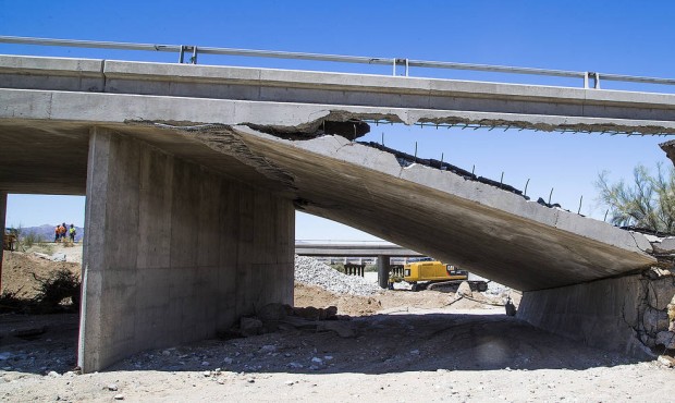 n Construction workers stand near the collapsed elevated section of Interstate 10, Wednesday, July ...