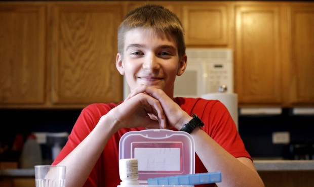 In this photo taken Wednesday, May 13, 2015, Hayden Murphy, 13, sits for a photo with his medicine ...