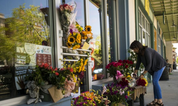 A woman leaves a bouquet of flowers at a makeshift memorial for store co-owner Jillian Johnson at R...