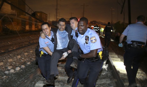 Emergency personnel help a passenger at the scene of a train wreck, Tuesday, May 12, 2015, in Phila...