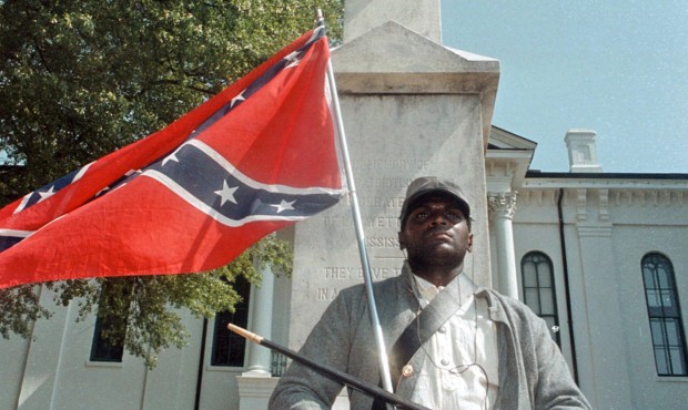FILE – In this May 8, 2000, file photograph, Anthony Hervey holds a Confederate flag while st...