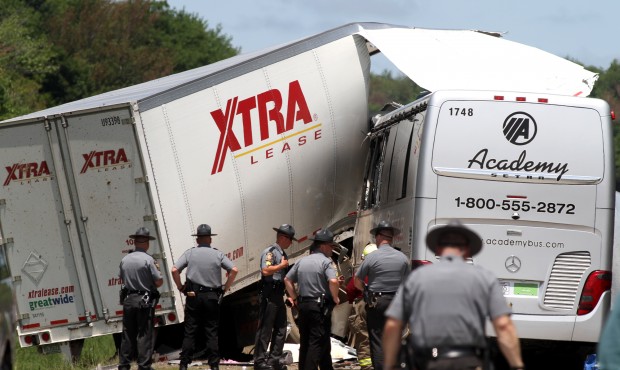 Authorities investigate the scene of a fatal collision between a tractor-trailer and a tour bus on ...